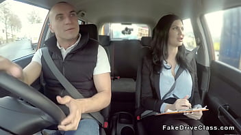 Vollbusige Brünette macht Oralsex im Auto, während sie nach einem Auto fährt